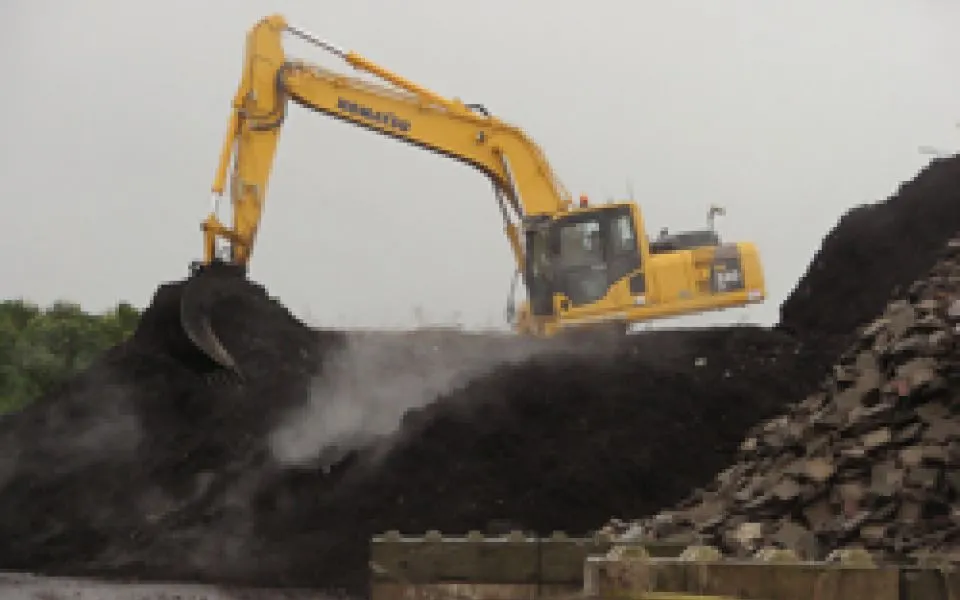 Rupskraan aan het werk op een dampende composthoop