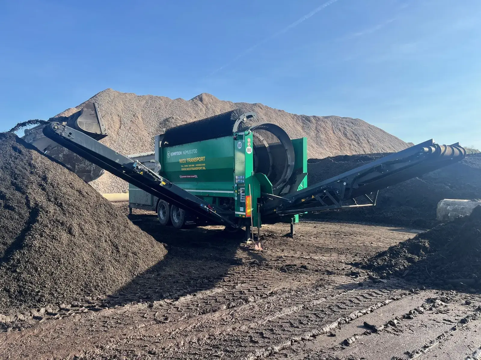 Zeefinstallatie tussen bergen zand en grond op een verwerkingsterrein